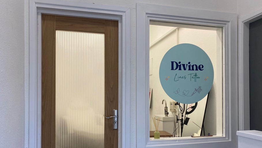 Entrance to Divine Line Tattoo studio in Newquay, England, GB, showing glass door and logo.