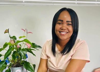 Warm smile at Aspire Beauty Studio in Jeffreys Bay, Eastern Cape, ZA. Lush plant decorates the serene setting.