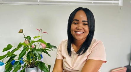 Warm smile at Aspire Beauty Studio in Jeffreys Bay, Eastern Cape, ZA. Lush plant decorates the serene setting.