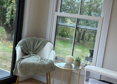 Cozy chair with green blanket by window at The Forge Beauty Room, Newsham, England, GB.
