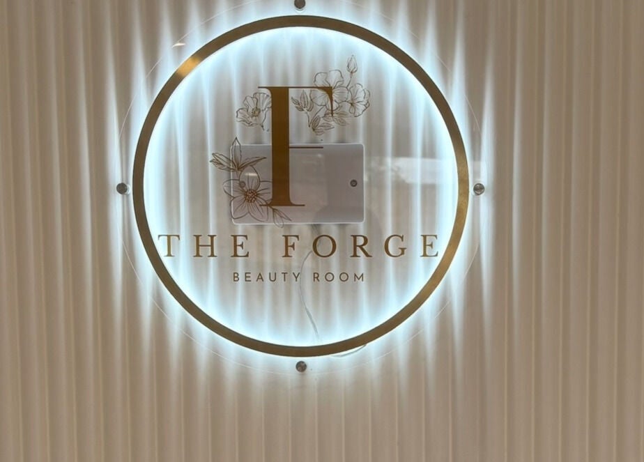 Illuminated sign of The Forge Beauty Room at Newsham, England, GB showcasing elegant design.