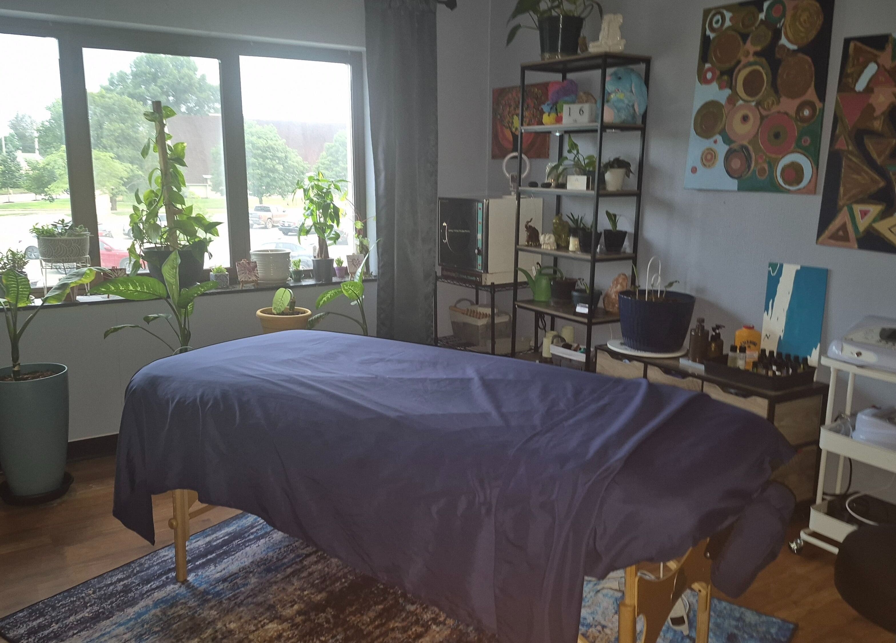 Relaxing massage room at Mo'Living Massage & Studio LLC, Columbus, Ohio with greenery and art decor.