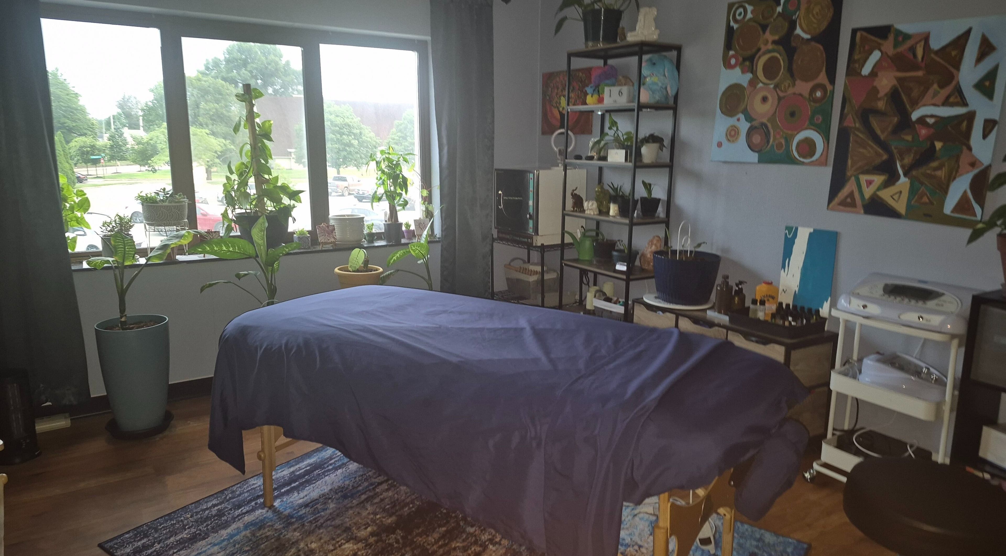 Relaxing massage room at Mo'Living Massage & Studio LLC, Columbus, Ohio with greenery and art decor.