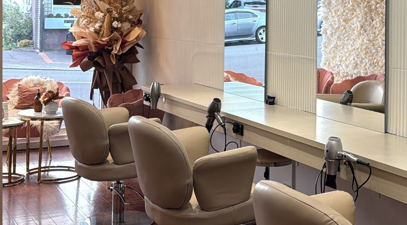 Chic styling area at Zen Hair Co, Auckland, NZ with plush chairs and mirrors reflecting serene ambiance.