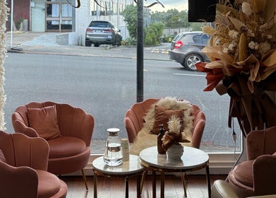 Chic lounge area at Zen Hair Co, Auckland, NZ featuring plush pink chairs and elegant decor.