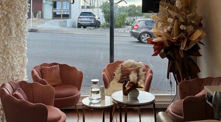 Chic lounge area at Zen Hair Co, Auckland, NZ featuring plush pink chairs and elegant decor.