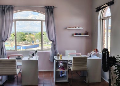 Bright nail salon interior at Prim Nails Skin Hair, Pretoria, Gauteng, ZA with nail polish shelves and seating.