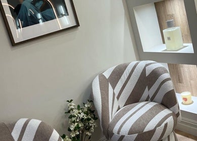 Comfortable seating area at EMMLOU BEAUTY, Cheadle Hulme, England, GB with stylish chairs and decorative display.
