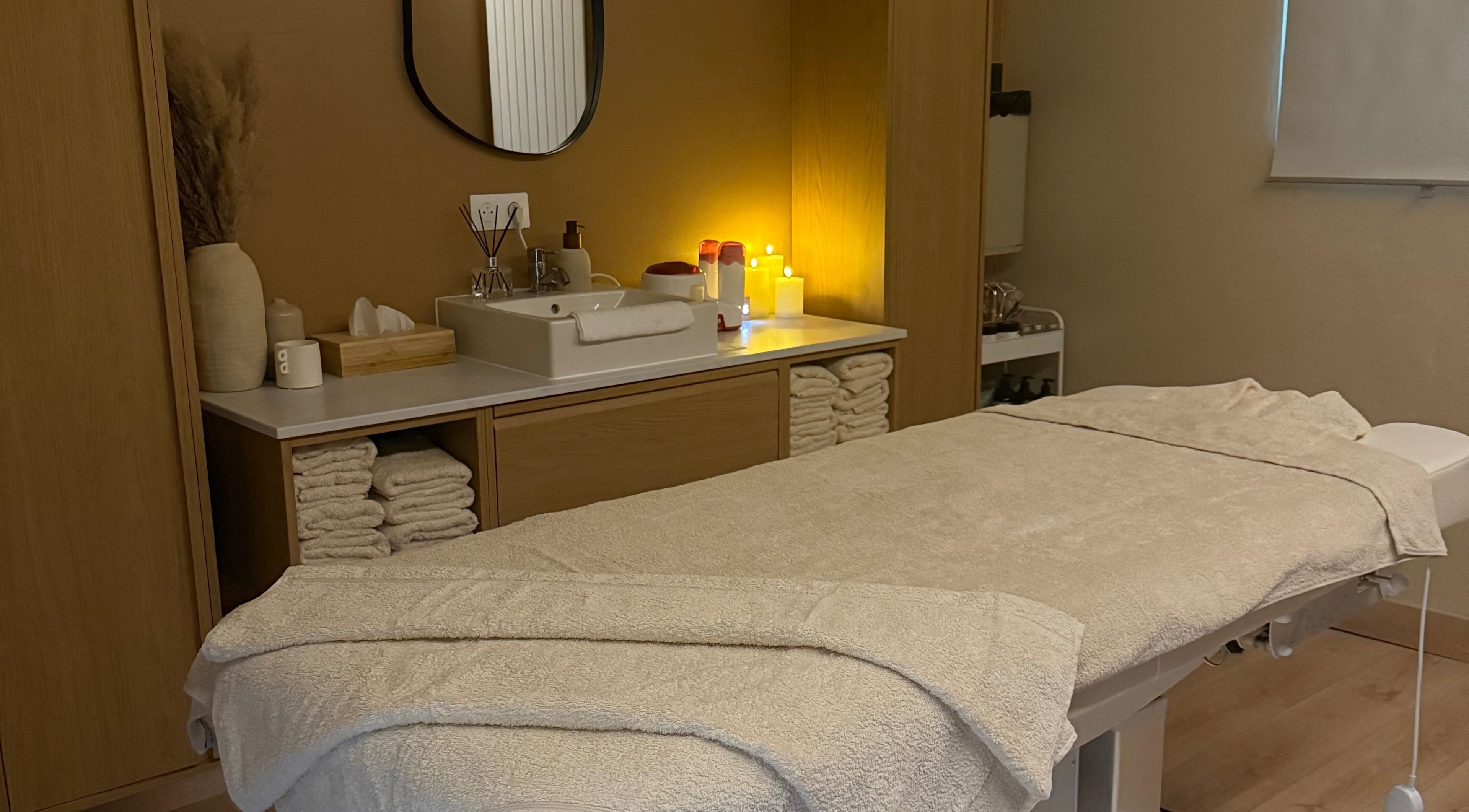 Salle de soins relaxante chez Oserenité, Aubrives, Grand Est, FR, avec table de massage et serviettes.