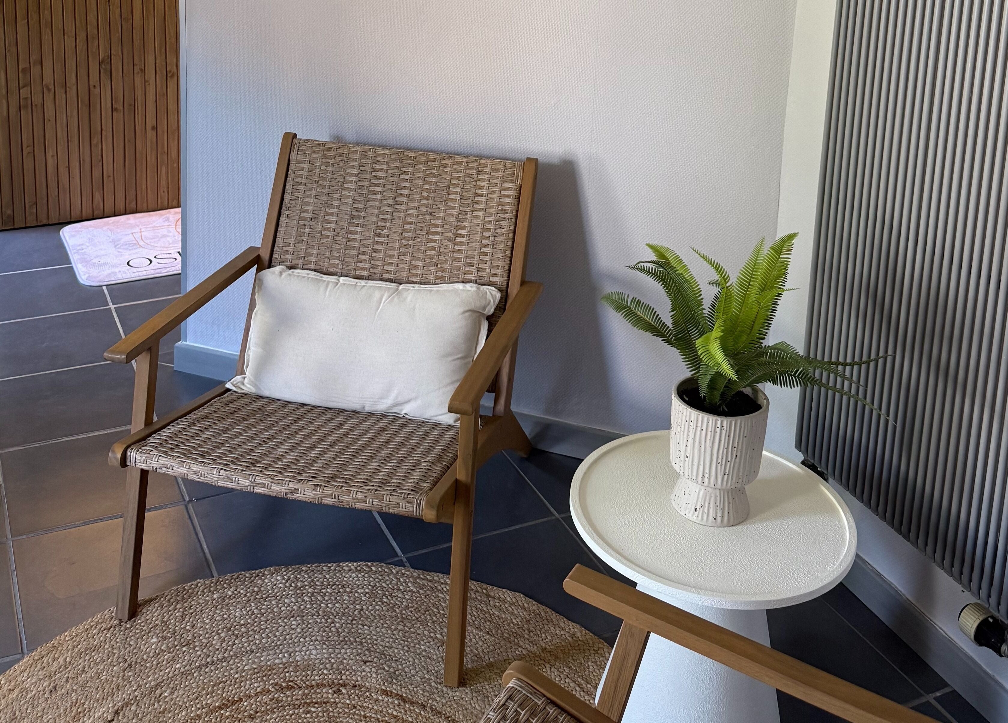 Coin détente avec chaise en osier et plante à Oserenité, Aubrives, Grand Est, FR.