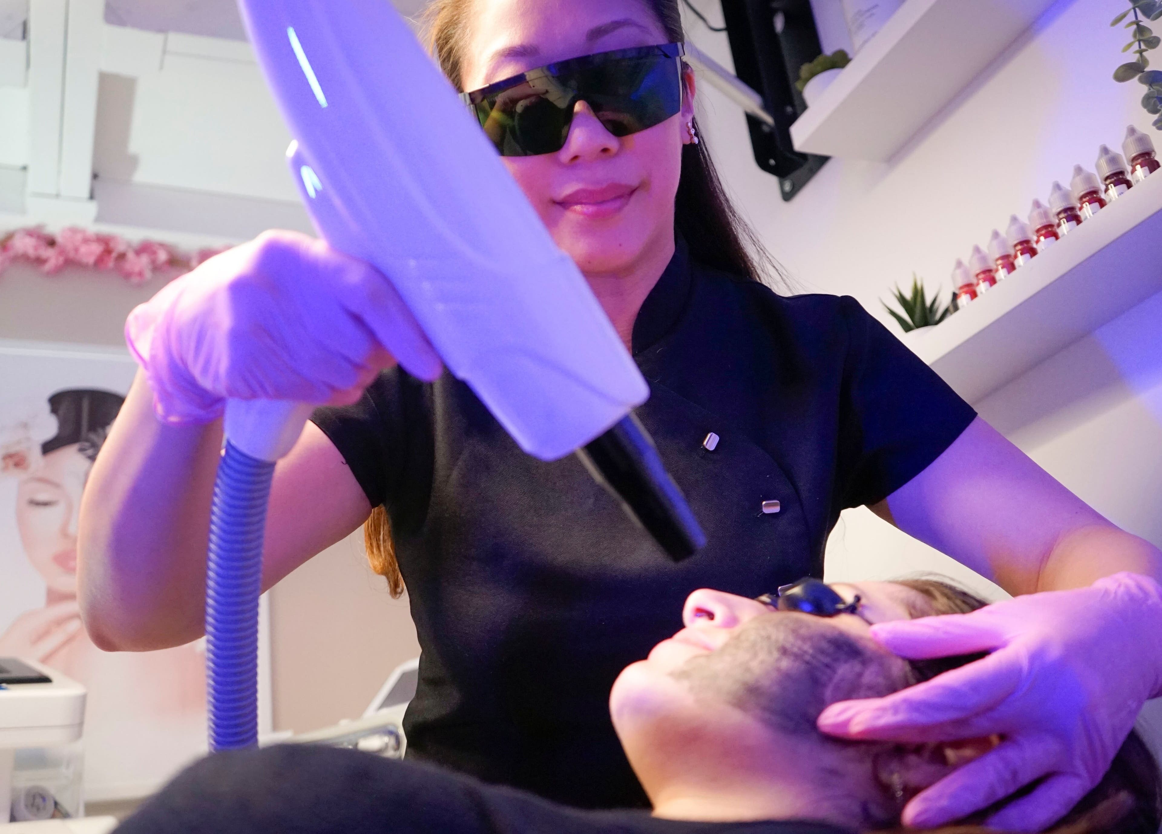 Laser treatment at Fine Line Studios, London, England, GB. A professional performing facial laser care.