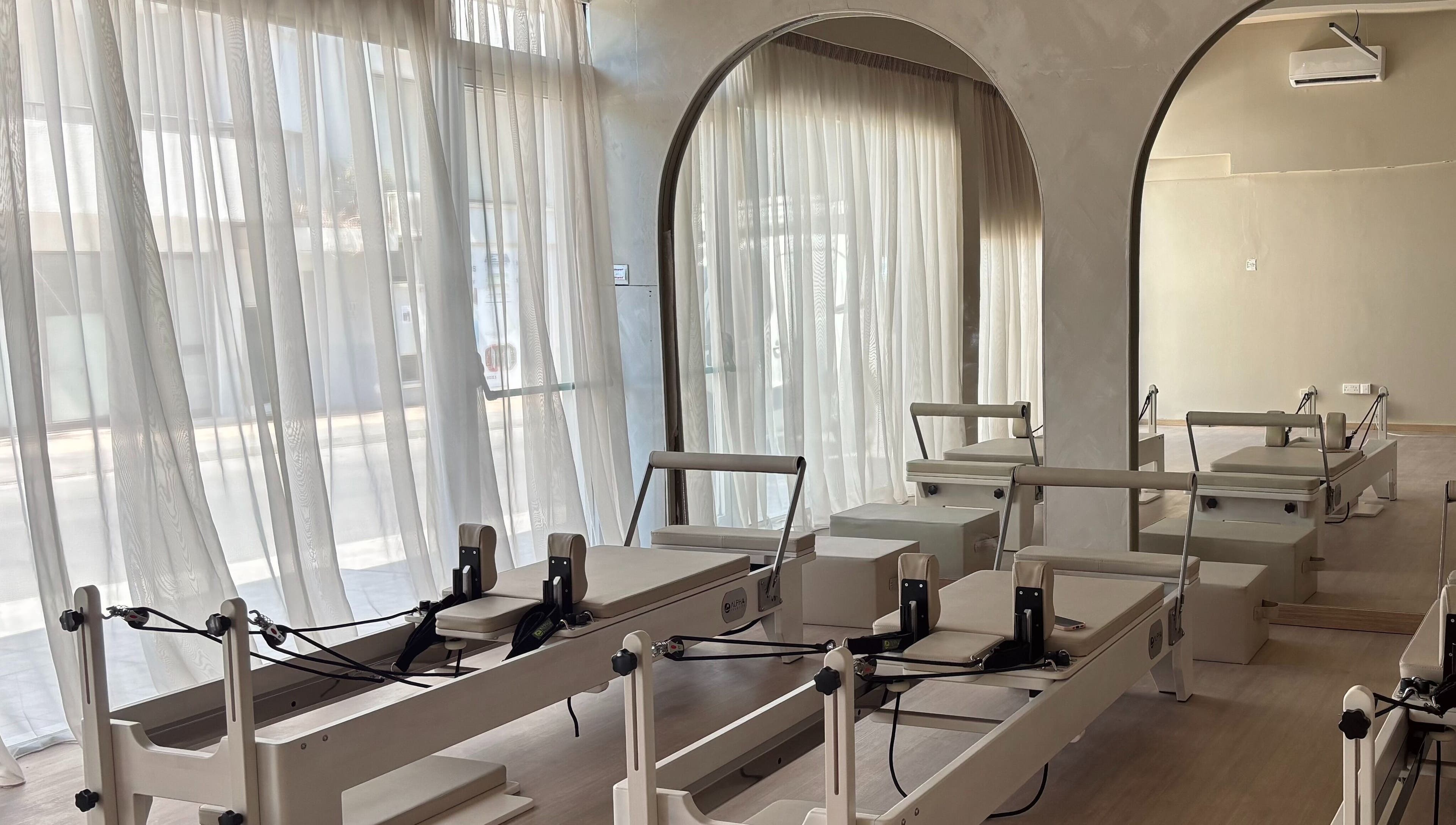 Pilates reformers at Aurora Pilates Studio, Strovolos, Lefkosia, CY with soft natural light filtering through curtains.