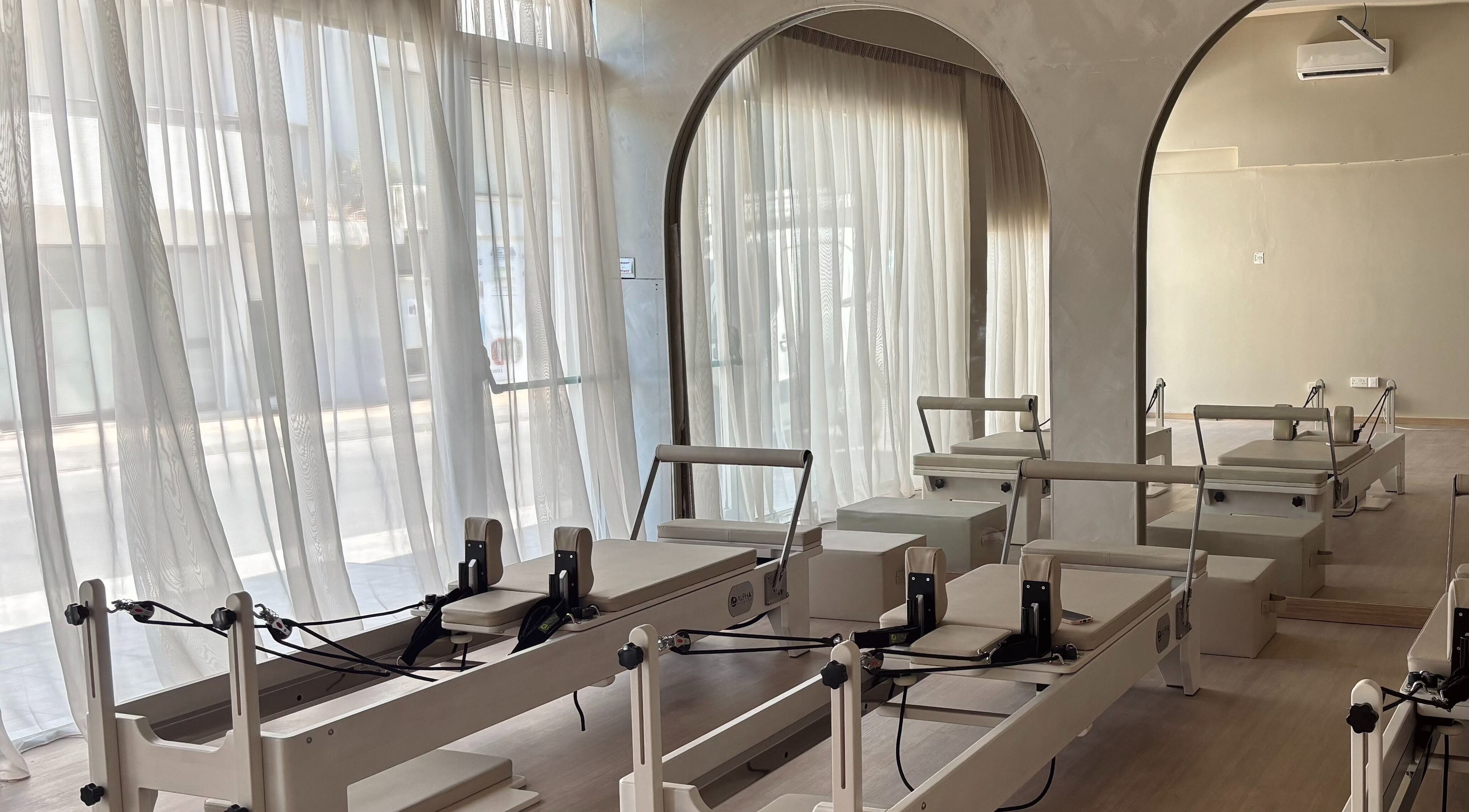 Pilates reformers at Aurora Pilates Studio, Strovolos, Lefkosia, CY with soft natural light filtering through curtains.