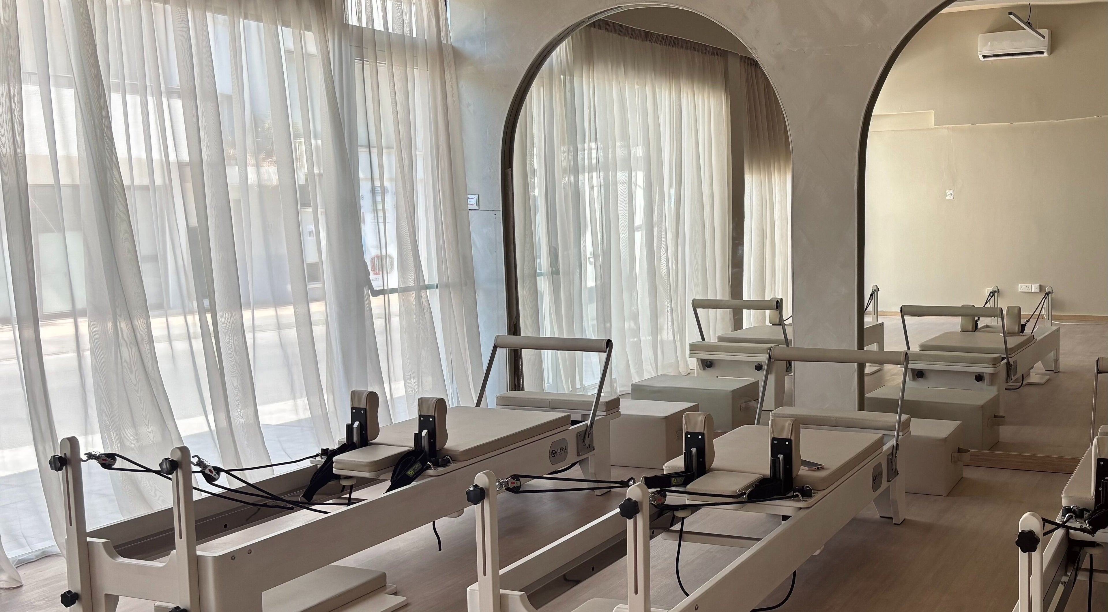 Pilates reformers at Aurora Pilates Studio, Strovolos, Lefkosia, CY with soft natural light filtering through curtains.