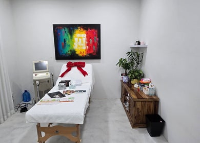 Skash treatment room in Cape Town, Western Cape, ZA, with a bed, art, and plants for a serene experience.