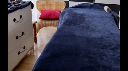 Salle de massage chez Nat & Sens à Maisons-laffitte, Île-de-france, FR avec lit bleu et chaise en osier.