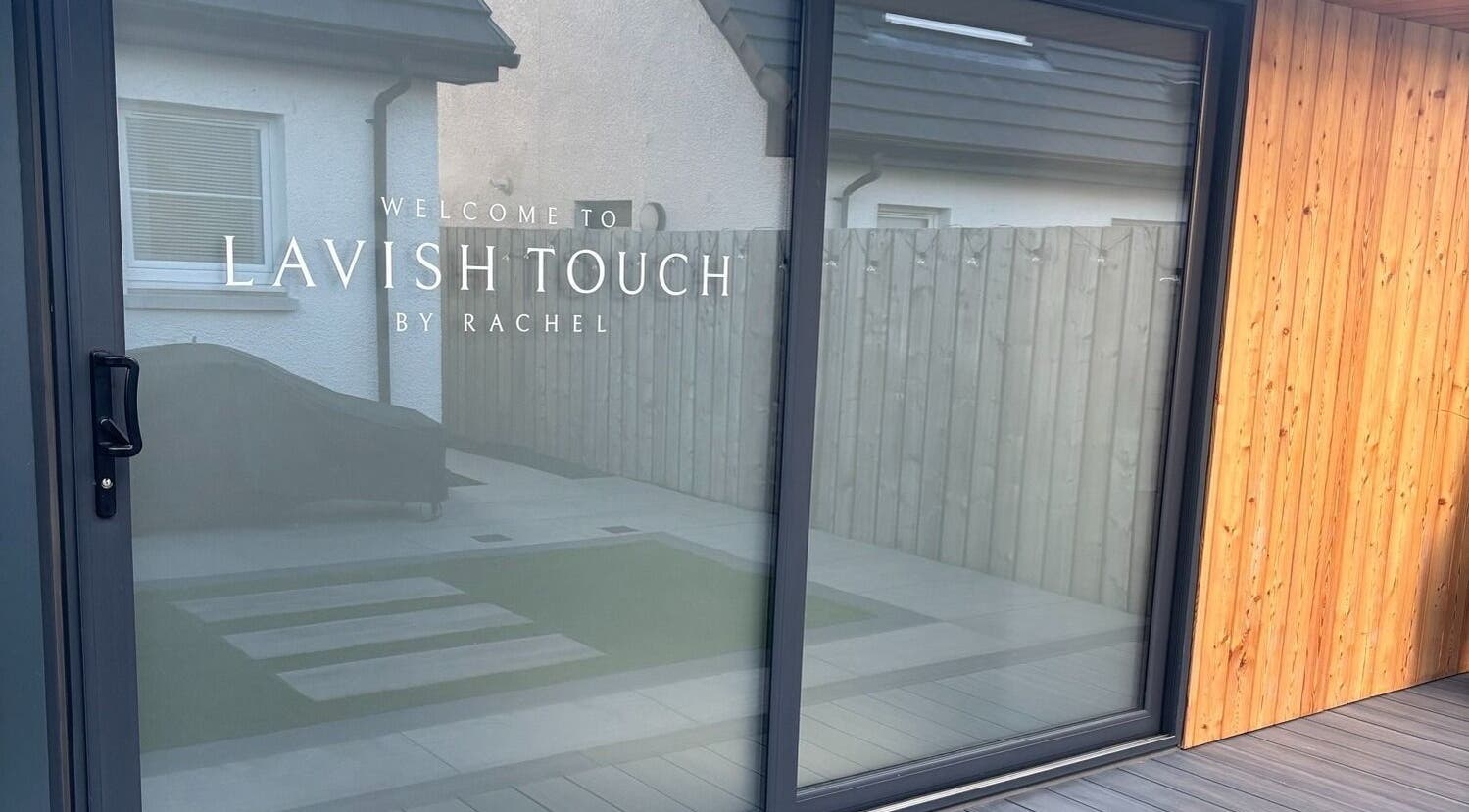 Entrance to Lavish Touch Dundee in Scotland, featuring a modern glass facade and warm wooden paneling.