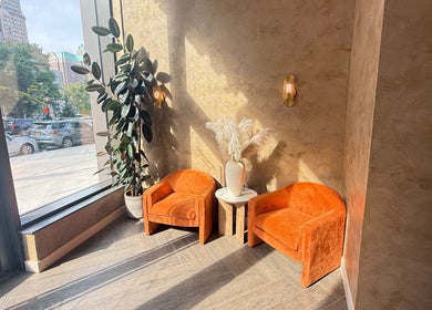 Bright seating area at Silky | The Healthy Hair Experts in New York, New York, US with orange chairs and natural light.