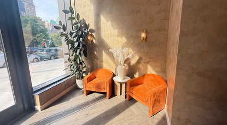 Bright seating area at Silky | The Healthy Hair Experts in New York, New York, US with orange chairs and natural light.