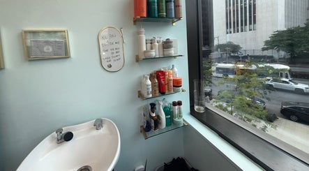 Hair products and sink by a window at Silky | The Healthy Hair Experts, New York, New York, US.