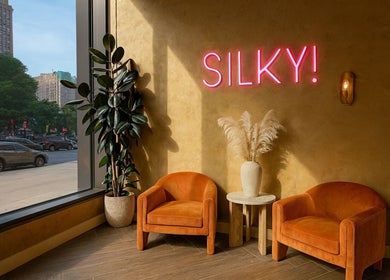 Cozy lounge at Silky | The Healthy Hair Experts, New York, New York, US with neon sign, chairs, and decor.