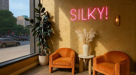 Cozy lounge at Silky | The Healthy Hair Experts, New York, New York, US with neon sign, chairs, and decor.