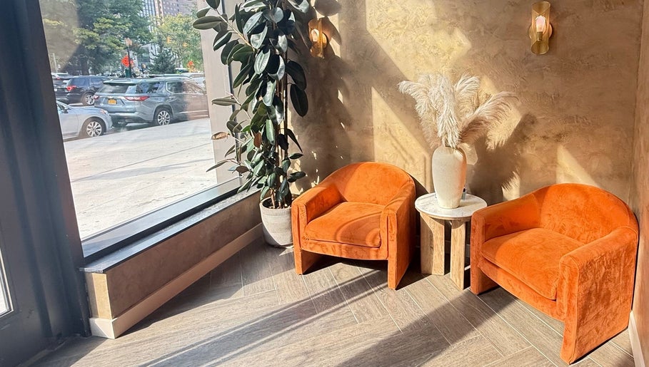 Cozy waiting area with orange chairs at Silky | The Healthy Hair Experts, New York, New York, US.