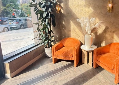 Cozy waiting area with orange chairs at Silky | The Healthy Hair Experts, New York, New York, US.