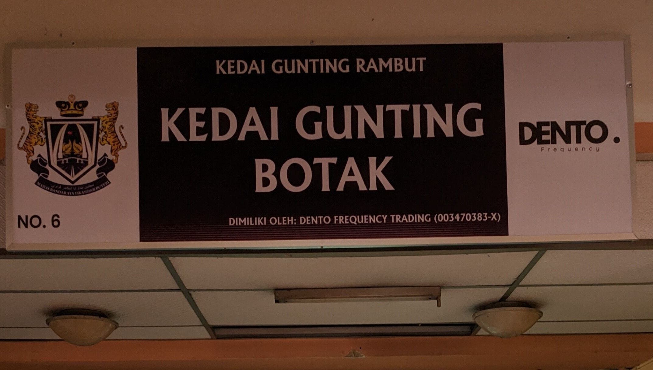 Signage of Kedai Gunting Botak in Skudai, Johor Darul Ta'zim, MY, showcasing barber's logo.