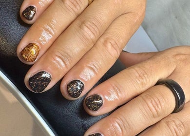 Elegant glitter nail art at Nails by Delle, Dingwall, Scotland, GB, showcasing golden sparkle on a dark base.