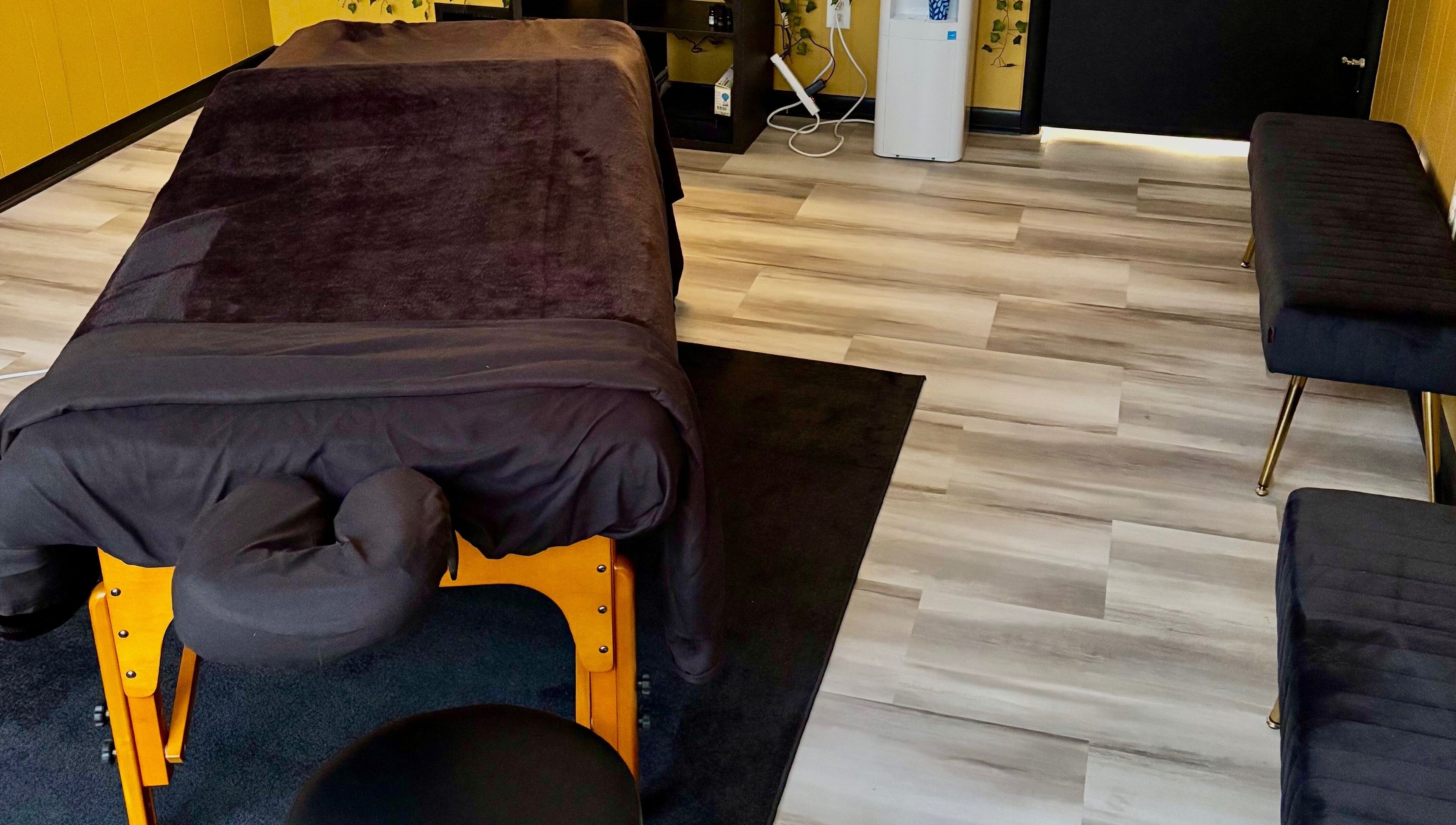 Cozy massage room setup at Serenity’s Remedies in Toledo, Ohio, US featuring a massage table and plush seating.