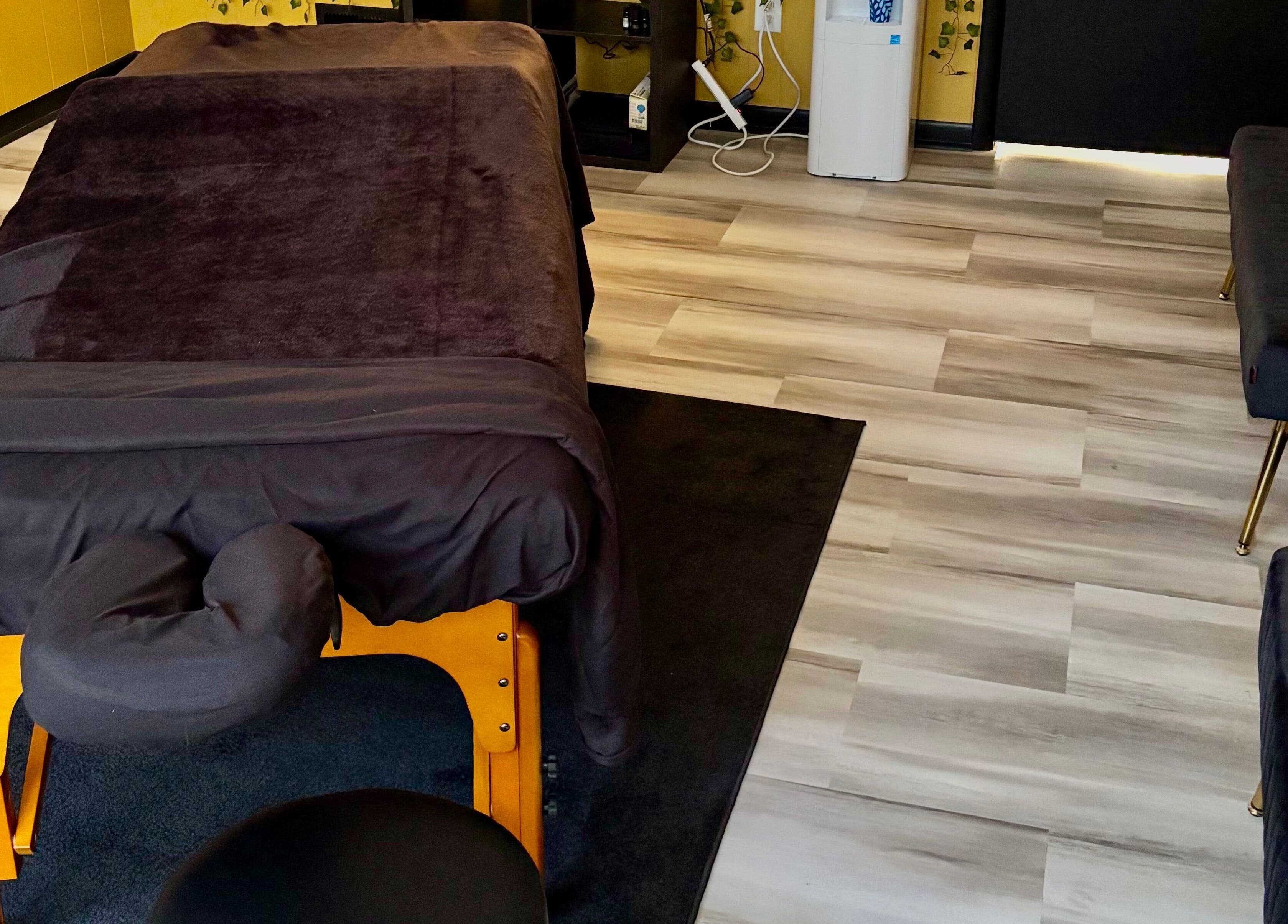 Cozy massage room setup at Serenity’s Remedies in Toledo, Ohio, US featuring a massage table and plush seating.