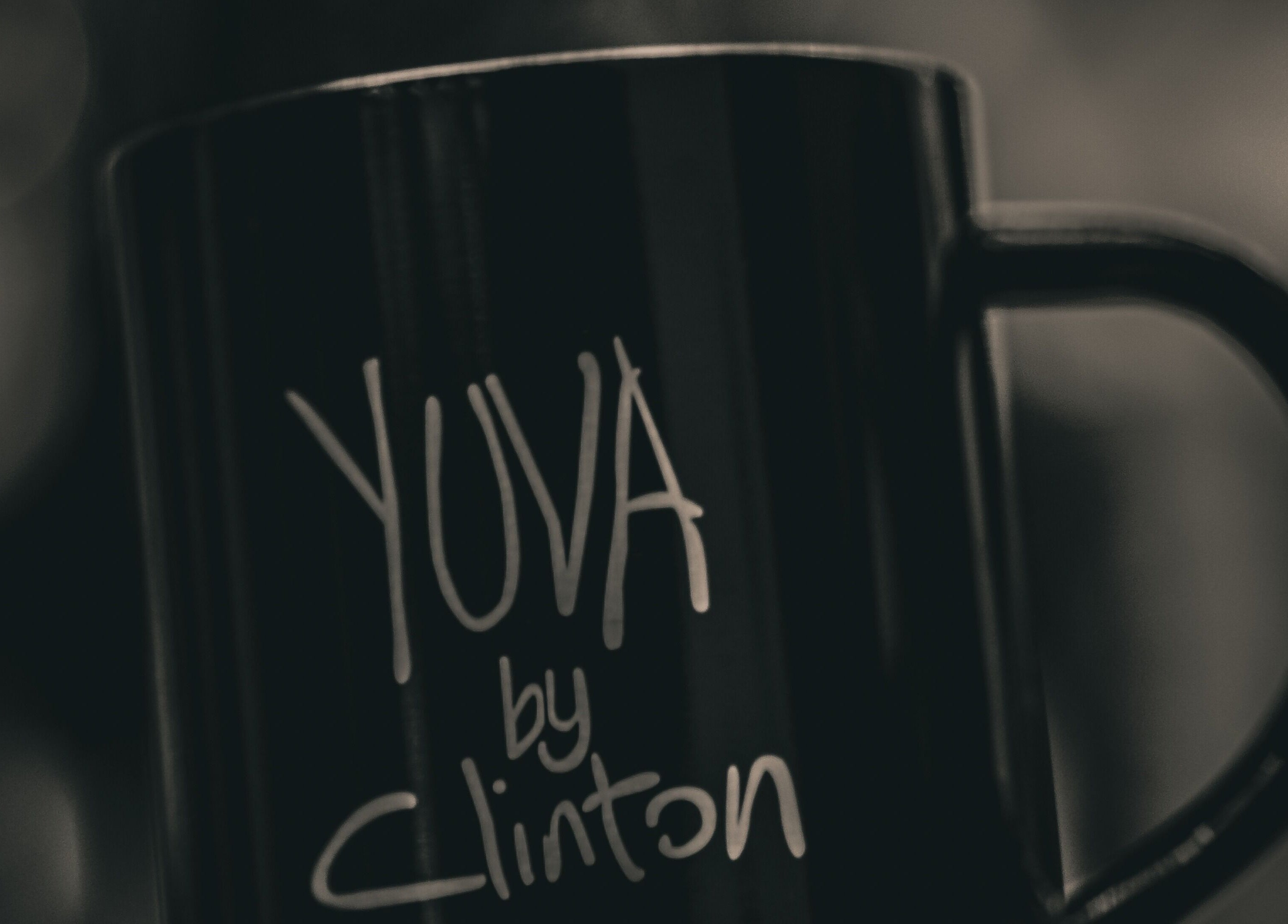 Close-up of a black mug with 'Yuva by Clinton' logo in Ħaż-Żebbuġ, MT.