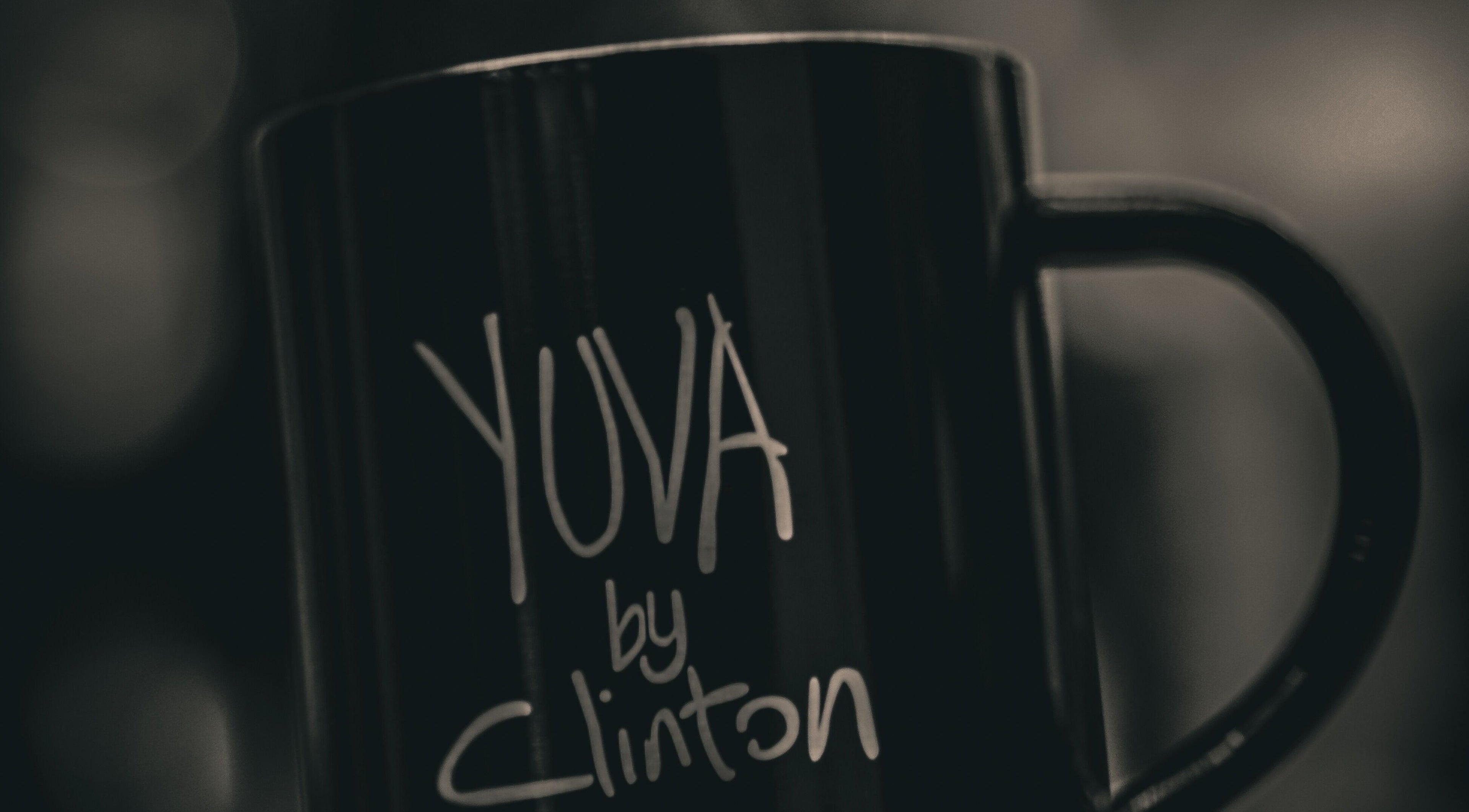 Close-up of a black mug with 'Yuva by Clinton' logo in Ħaż-Żebbuġ, MT.
