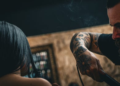 A stylist at Yuva by Clinton, Ħaż-Żebbuġ, MT, carefully straightens a client's hair.