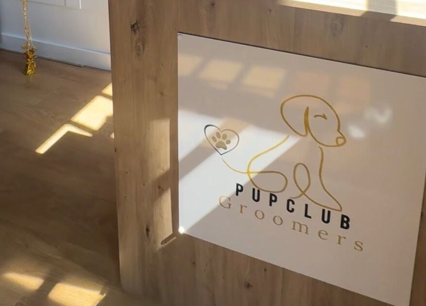 Pup Club Groomers logo on a welcoming wooden counter in Birmingham, England, GB.