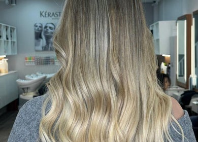 Elegant blonde waves styled at HAIR COLLECTIVE, London, England, GB. Modern salon interior in background.