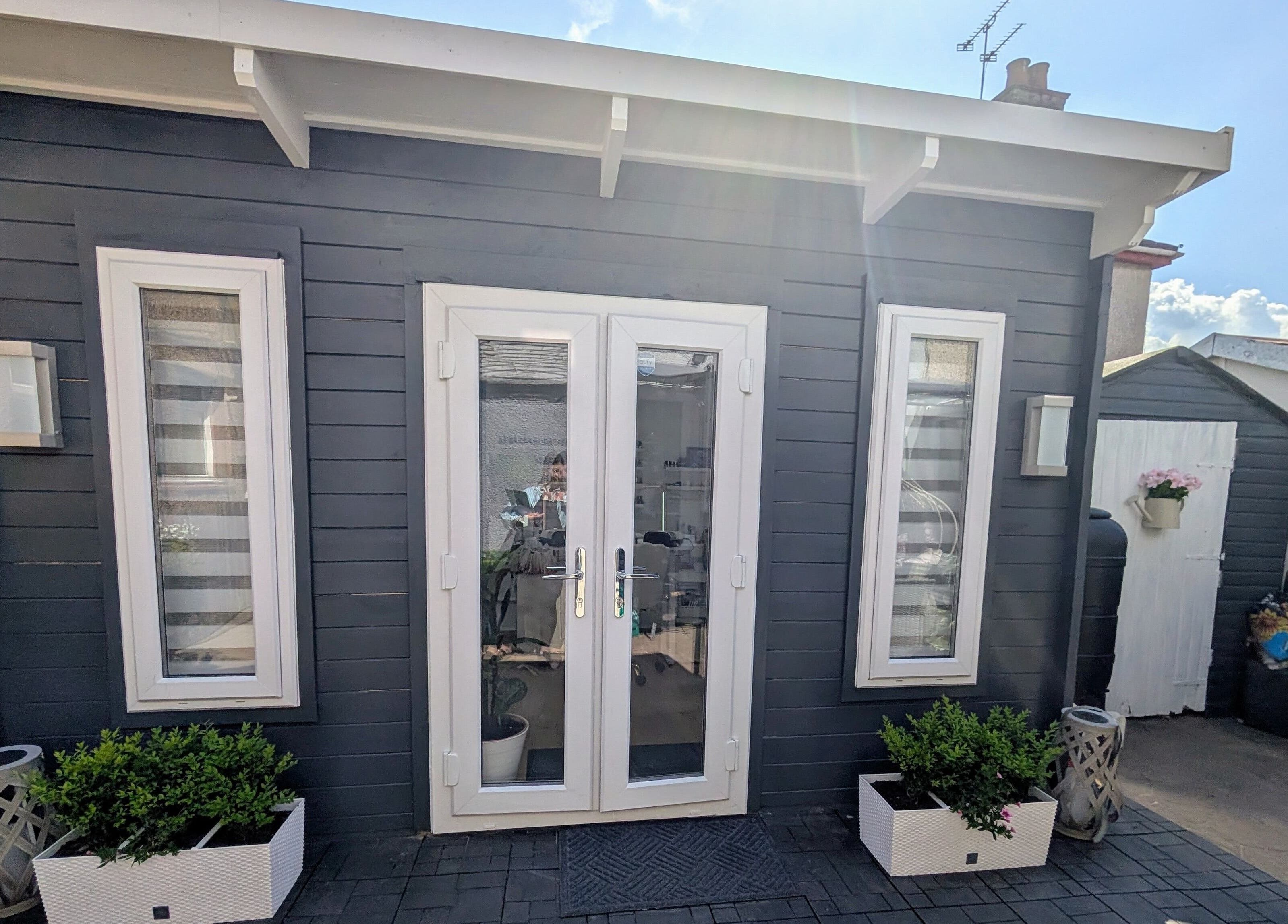 Modern entrance of Beauty by Viv in Llandudno Junction, Wales, GB, with sleek black facade and potted plants.