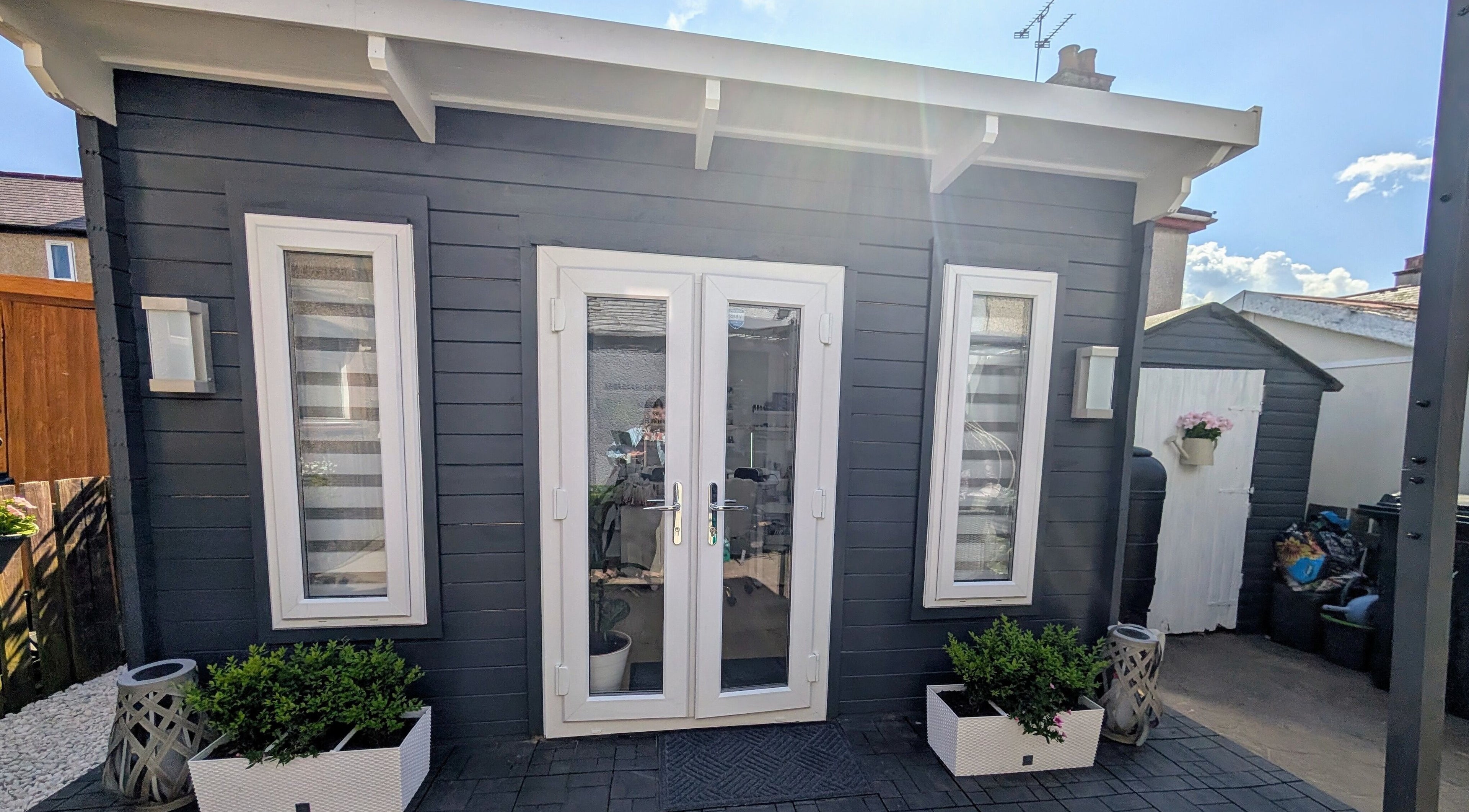Modern entrance of Beauty by Viv in Llandudno Junction, Wales, GB, with sleek black facade and potted plants.