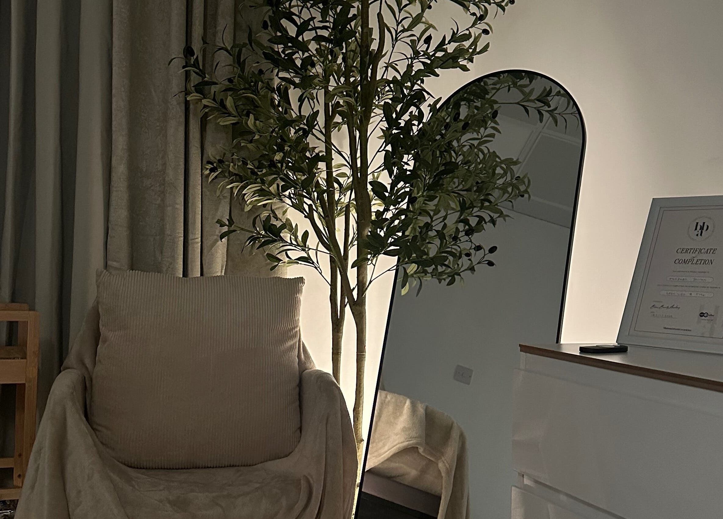 Relaxing corner at Browtopia & Beyond | Halal Brows in London, England, GB with a chair and decorative tree.