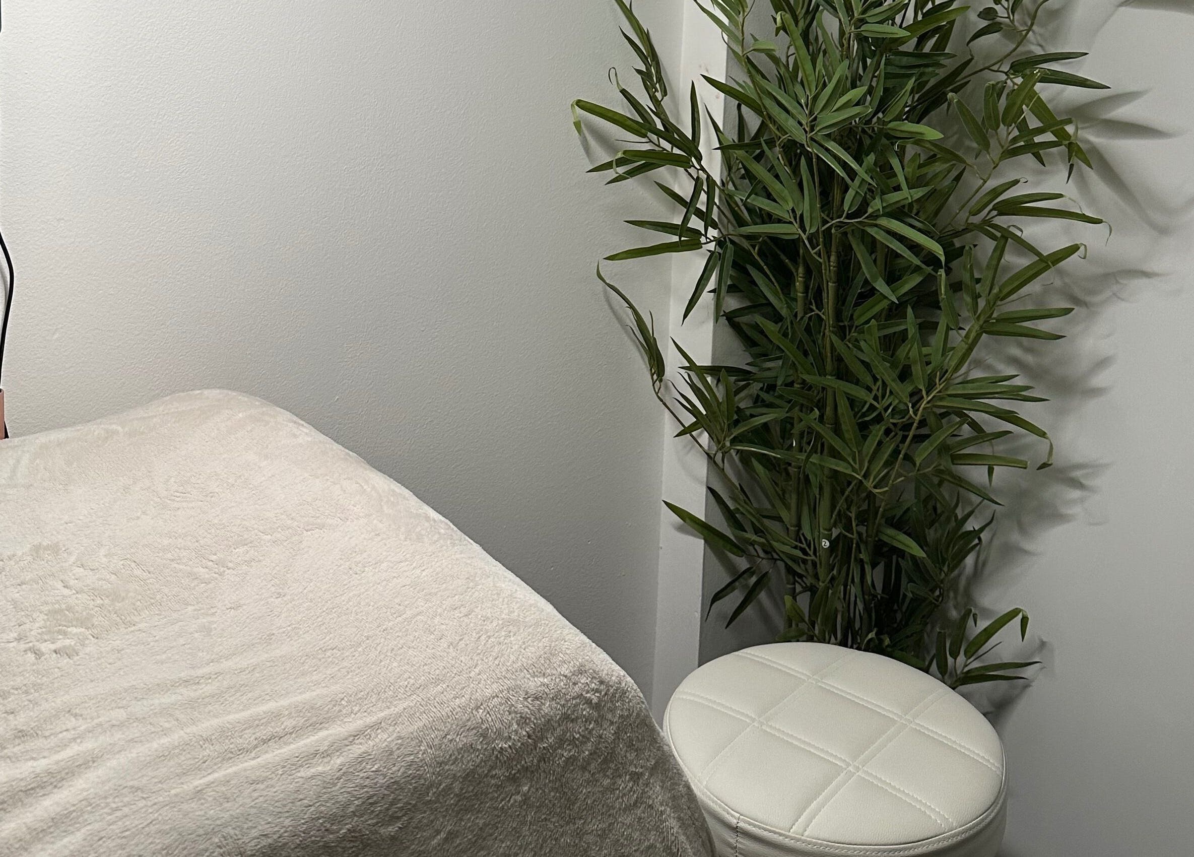 Elegant treatment room at Browtopia & Beyond | Halal Brows, London, England, GB with white stool and lush plant.