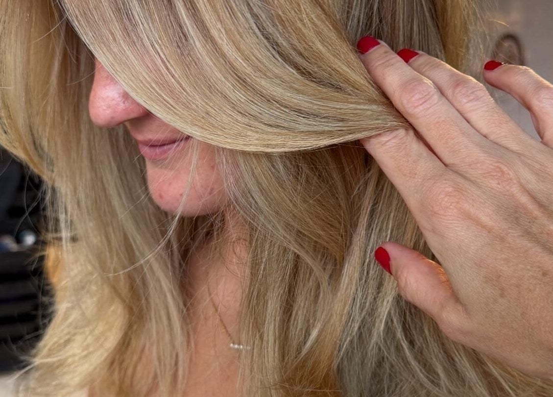 Blonde hair styled at Simone West Hair Makeup in Landsborough, Queensland, AU with hand showcasing layers.