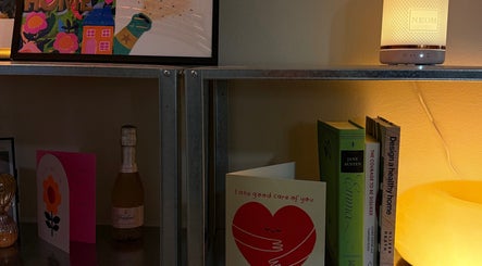 Warm-lit shelf at emstudio, Clydebank, Scotland, GB, with books, cards, and a glowing lamp.
