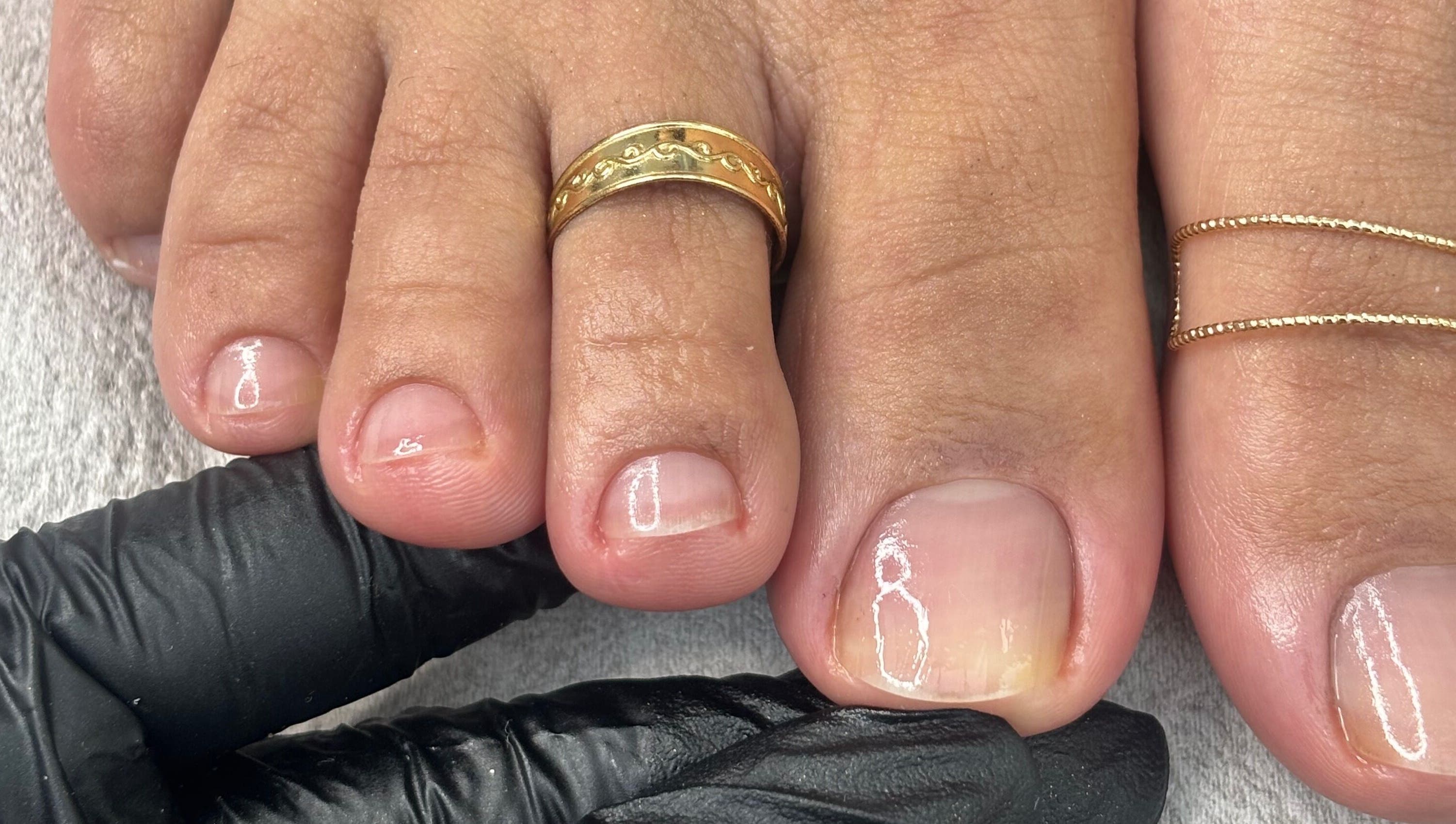 Close-up of manicured toenails with gold rings at Mani.festation.nbt, Mountsorrel, England, GB.