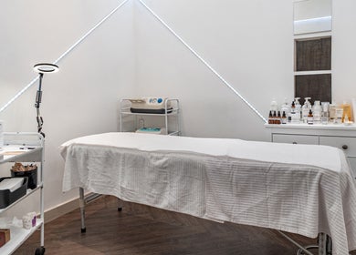 Tranquil spa treatment room at It's Angies, London, England, GB with massage table and skincare products.