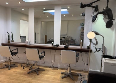 Interior of Gianni Hair salon in London, England, GB, featuring modern styling chairs and mirrors.