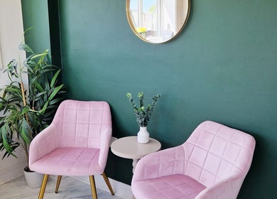 Cozy seating area at Nordik Aesthetics @ Dahlin, Sandbach, England, GB, with pink chairs and green wall.