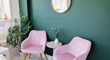Cozy seating area at Nordik Aesthetics @ Dahlin, Sandbach, England, GB, with pink chairs and green wall.
