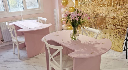 Chic pink nail salon setup at Nordik Aesthetics @ Dahlin, Sandbach, England, GB with flowers and gold decor.