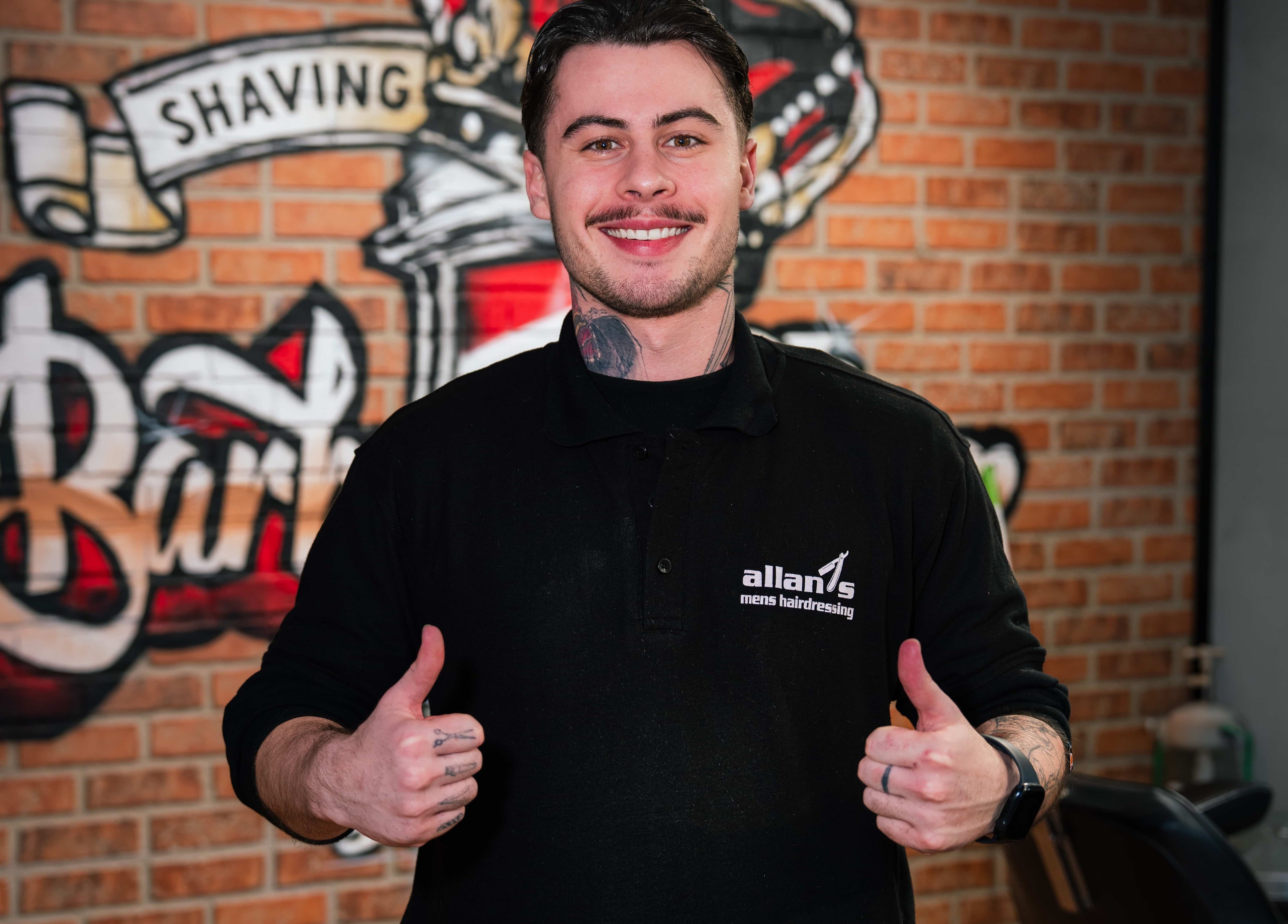 Barber at Allan's Men's Hairdressing - Warrabrook, New South Wales, AU, smiles confidently in front of salon decor.